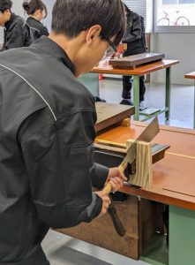 木型の材料の板をのこぎりで切断する様子